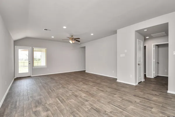 a view of an empty room with window and wooden floor