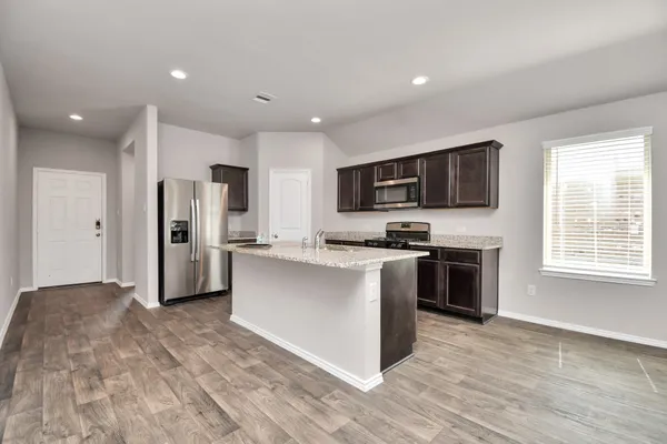 a kitchen with stainless steel appliances kitchen island granite countertop a stove a sink and a refrigerator
