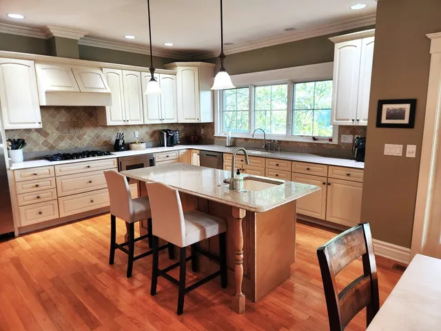 a kitchen with stainless steel appliances granite countertop a stove a sink a microwave a dining table and chairs with wooden floor