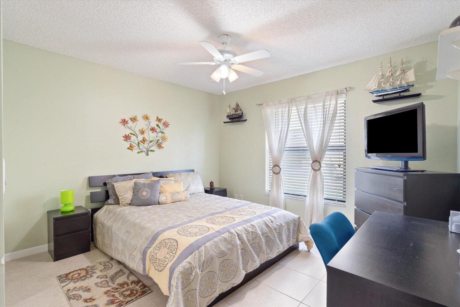 11241 Island Lakes Lane Boca Raton, FL 33498 - Photo 21 of 47 a bedroom with a large bed a flat tv screen and a chandelier