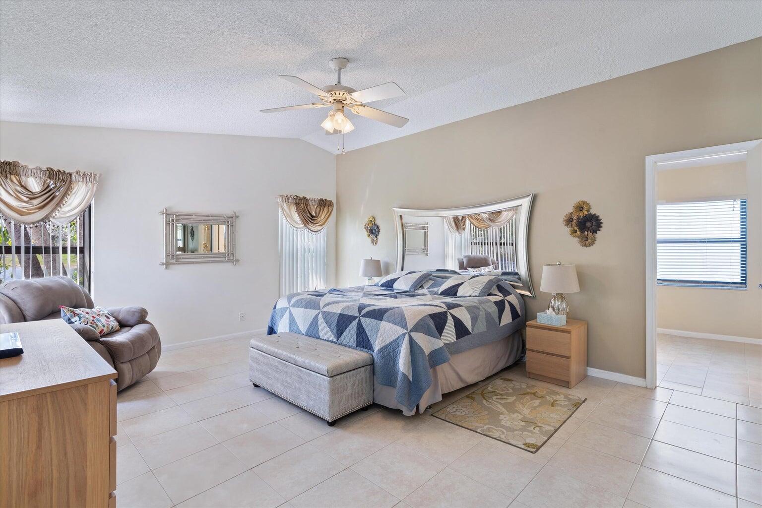 11241 Island Lakes Lane Boca Raton, FL 33498 - Photo 32 of 47 a spacious bedroom with a bed and a chandelier