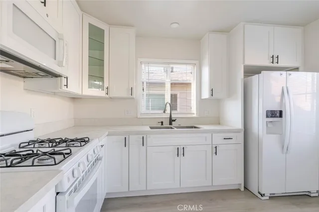 a white kitchen with stove top oven and sink