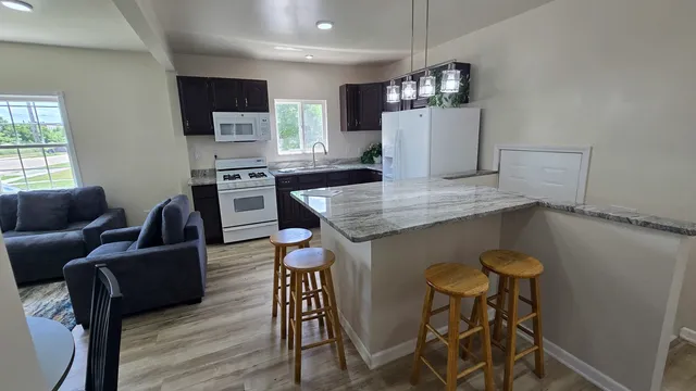 a kitchen with stainless steel appliances granite countertop a table chairs refrigerator and microwave