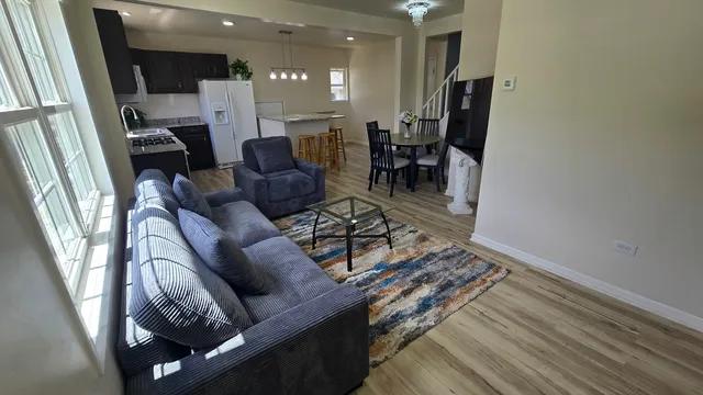 a living room with furniture a dining table and a refrigerator