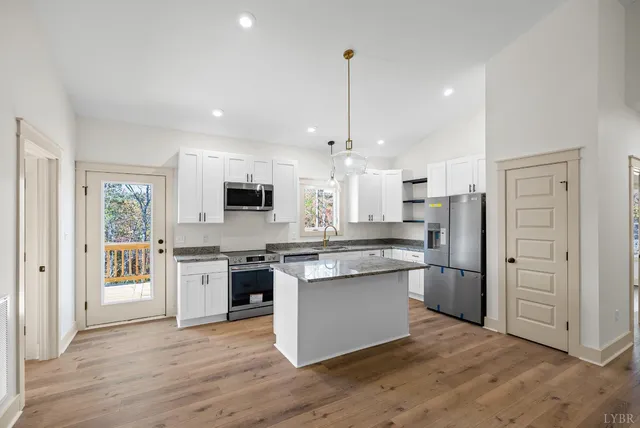 a kitchen with stainless steel appliances granite countertop a stove top oven a refrigerator and a sink