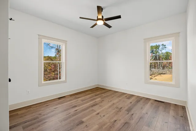 a view of empty room with wooden floor and fan