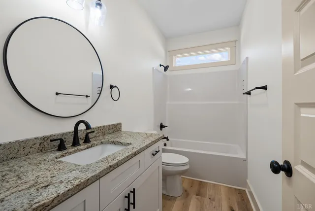 a bathroom with a granite countertop sink mirror vanity and toilet