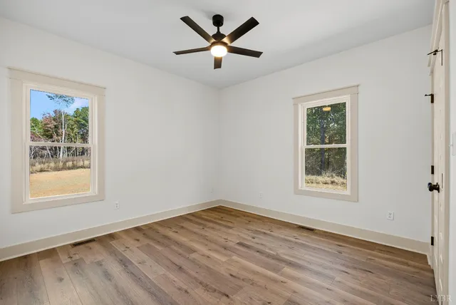 a view of an empty room with window and wooden floor