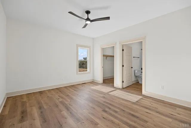 an empty room with wooden floor and a ceiling fan