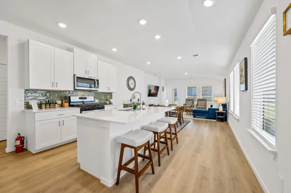 a large kitchen with stainless steel appliances granite countertop a lot of counter space and wooden floor