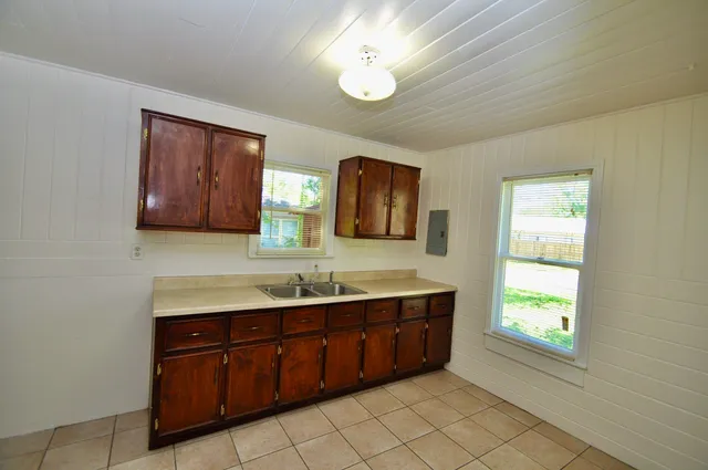 a view of an empty room with wooden floor and fan