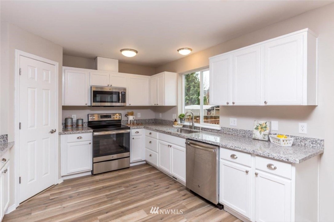8341 49th Loop Southeast Olympia, WA 98513 - Photo 11 of 25 a kitchen with granite countertop white cabinets stainless steel appliances a sink and a window