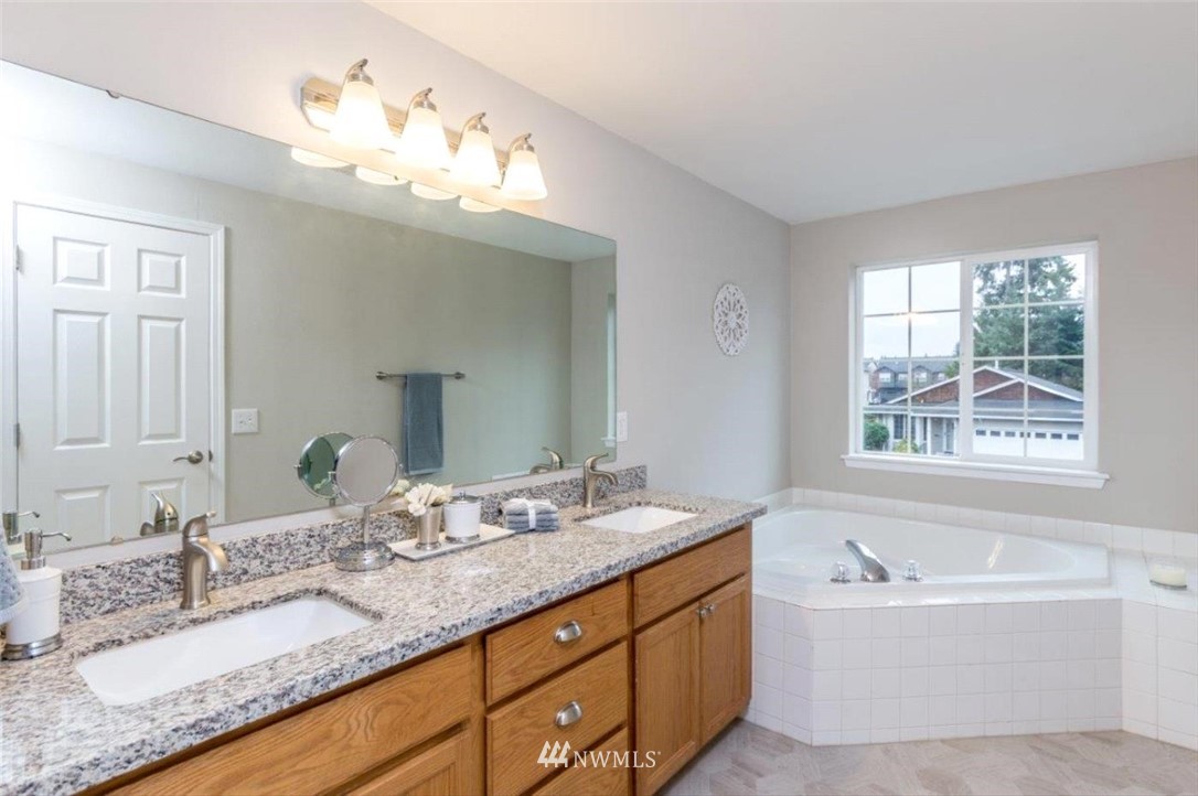 8341 49th Loop Southeast Olympia, WA 98513 - Photo 14 of 25 a bathroom with a granite countertop bathtub a sink and mirror