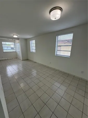 an empty room with windows and ceiling fan