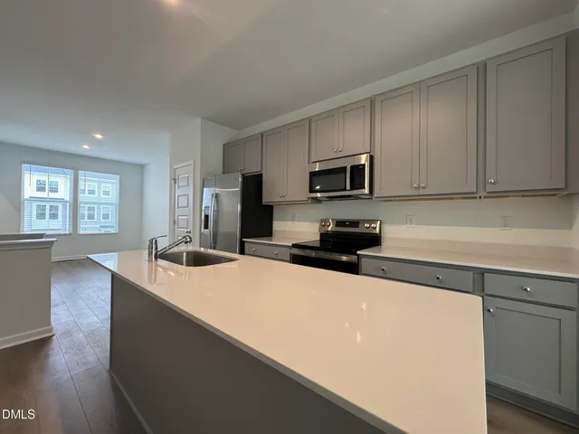 a kitchen with stainless steel appliances a sink a stove a microwave a sink a refrigerator and cabinets