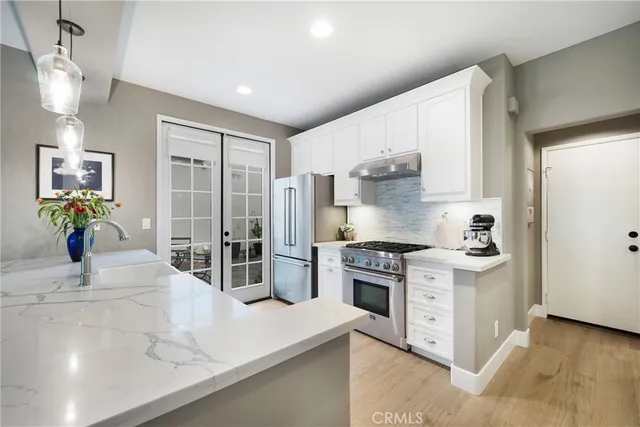 a large white kitchen with stainless steel appliances granite countertop a stove and a sink