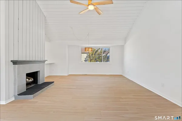 a view of an empty room with chandelier fan and fire place