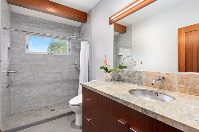 a bathroom with a granite countertop sink a toilet and shower