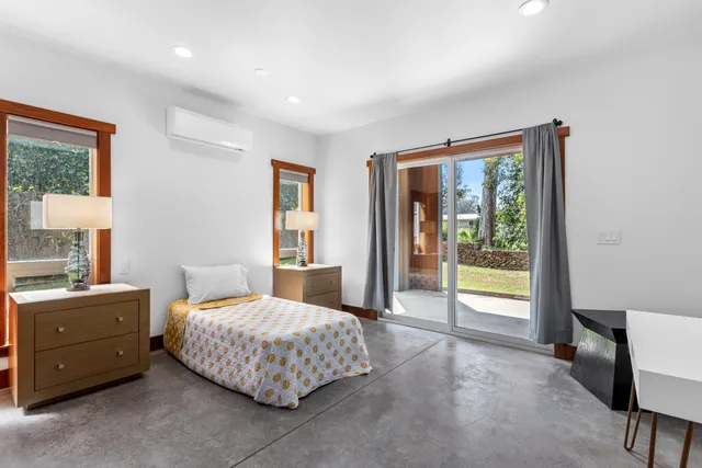 a bedroom with a bed and a dresser next to a window