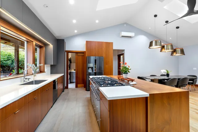 a kitchen with stainless steel appliances a stove a sink dishwasher and a refrigerator with wooden floor