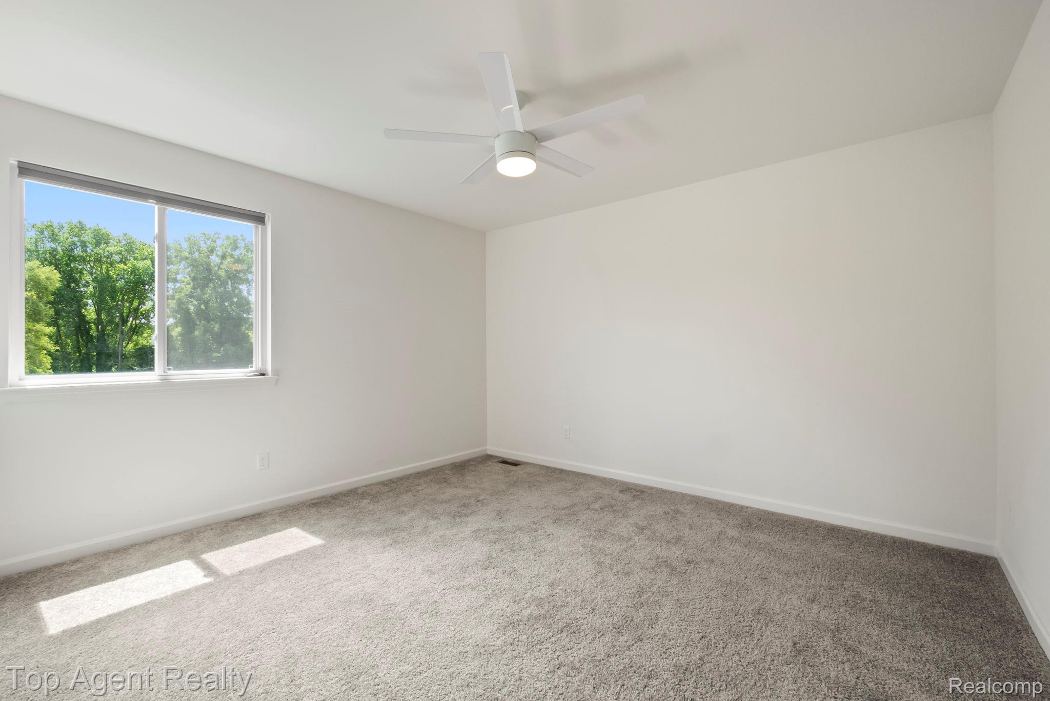 63770 Dequindre Road Washington, MI 48095 - Photo 38 of 61 Bright interior space featuring a window with natural scenery, light-toned carpet flooring, white walls, and a ceiling fan with integrated lighting