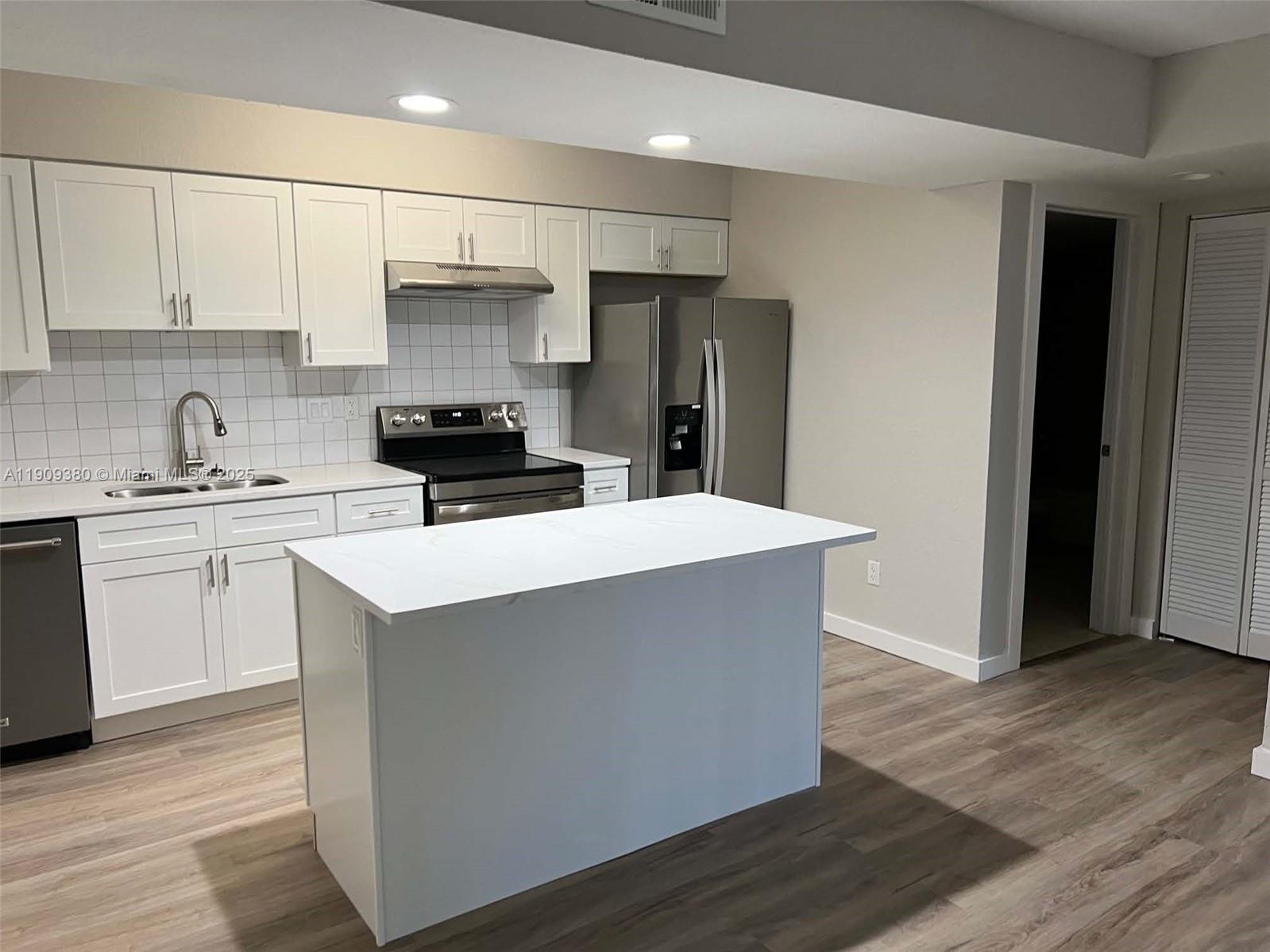 4055 West McNab Road, Unit H103 Pompano Beach, FL 33069 - Photo 5 of 14 a kitchen with kitchen island stainless steel appliances a sink stove and refrigerator