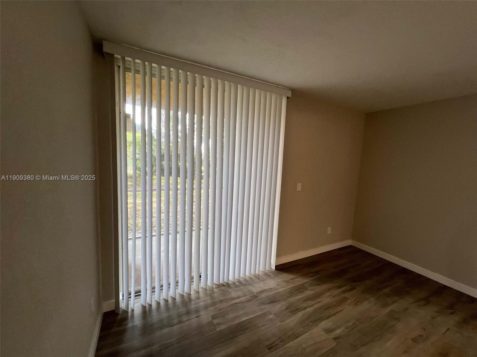 4055 West McNab Road, Unit H103 Pompano Beach, FL 33069 - Photo 6 of 14 an empty room with wooden floor and windows