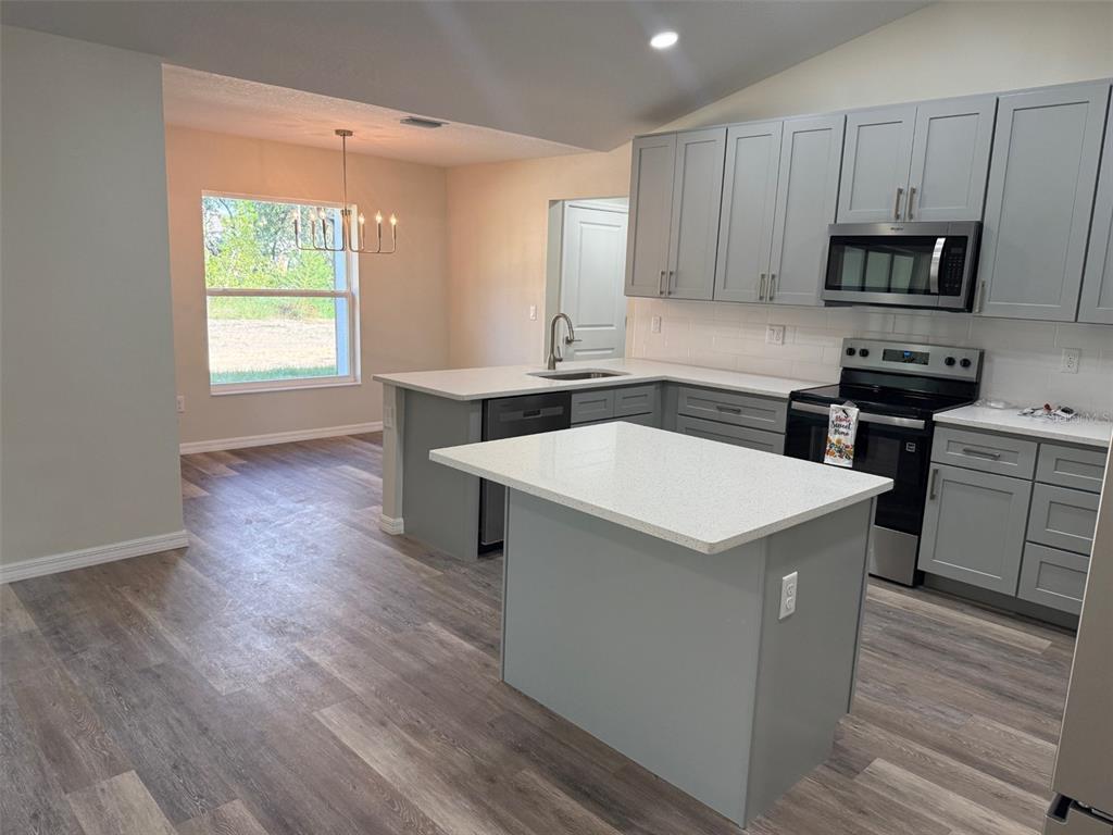 13465 Canyon Swallow Road Weeki Wachee, FL 34614 - Photo 4 of 22 a kitchen with stainless steel appliances a white stove top oven a sink dishwasher and a refrigerator with wooden floor