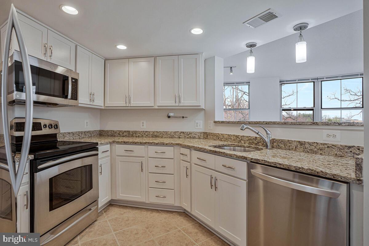 11800 Sunset Hills Road, Unit 514 Reston, VA 20190 - Photo 26 of 57 a kitchen with granite countertop white cabinets white stainless steel appliances and a sink