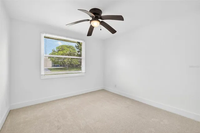 an empty room with a window and a fan