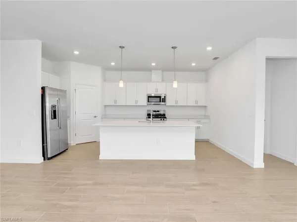 a view of kitchen with kitchen island white cabinets and stainless steel appliances