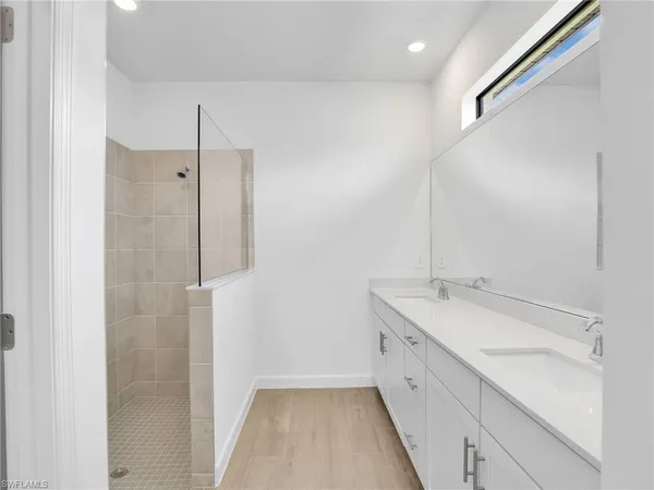 a spacious bathroom with a double vanity sink a mirror and a shower