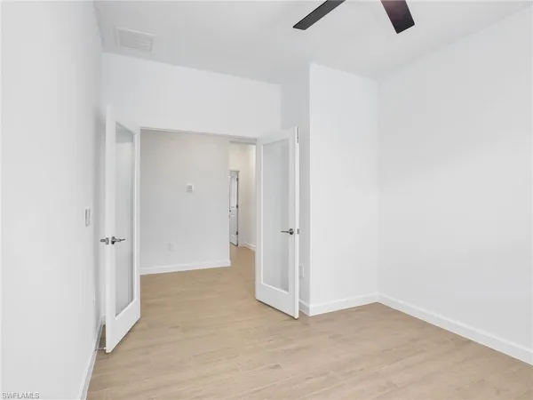 an empty room with windows and ceiling fan