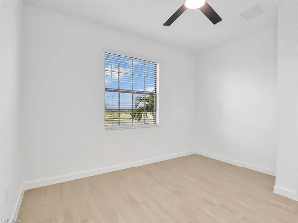 an empty room with ceiling fan and window