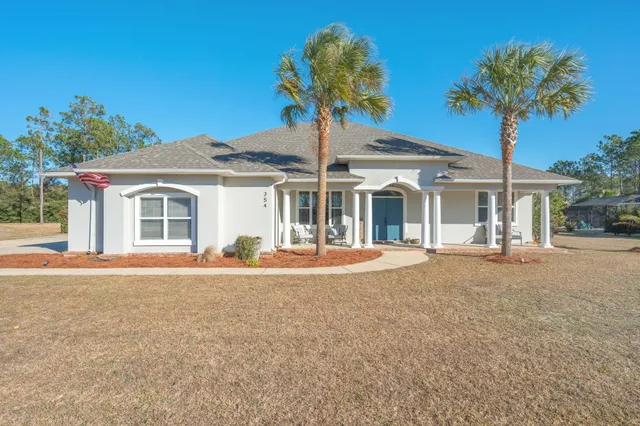 front view of a house with a yard and palm trees