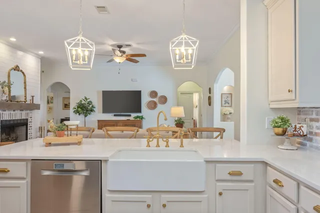 a kitchen with a sink dishwasher and white cabinets with wooden floor