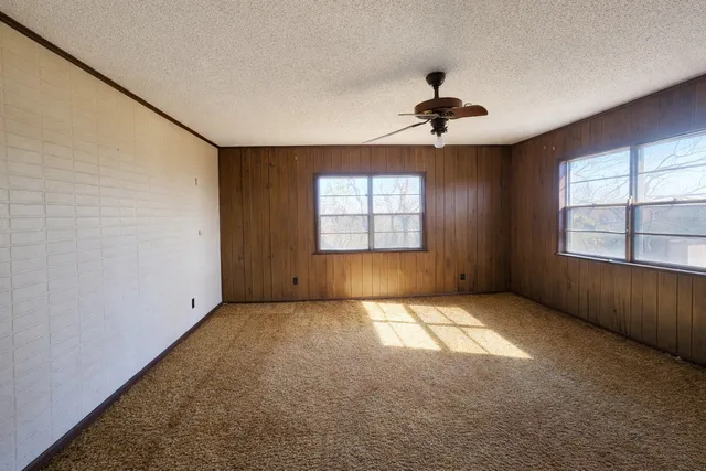 an empty room with windows and chandelier fan