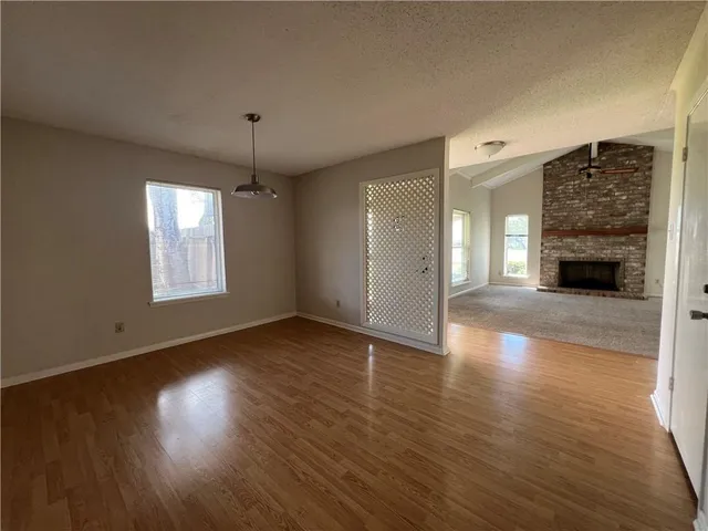 a view of an empty room with wooden floor fireplace and a window