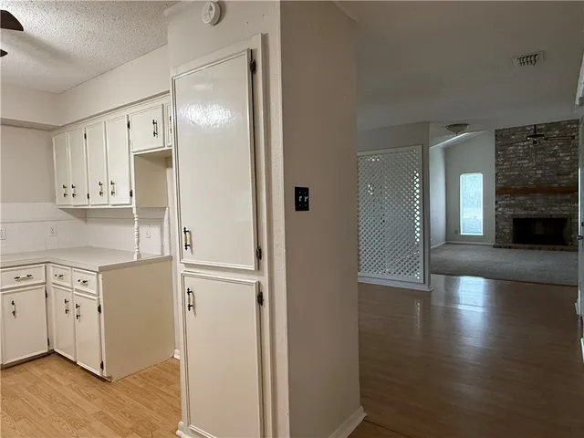 a view of a hallway with wooden floor and a kitchen