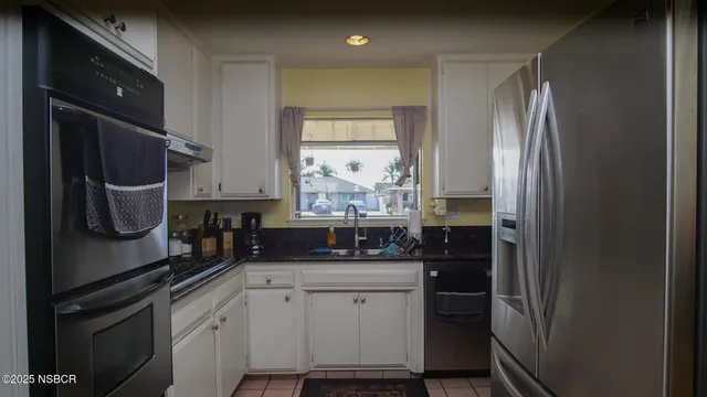 a kitchen with granite countertop a sink stainless steel appliances and cabinets