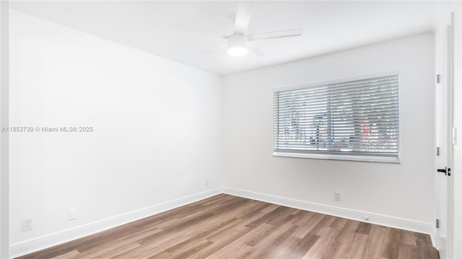 5686 Rock Island Road, Unit 106 Tamarac, FL 33319 - Photo 12 of 34 a view of an empty room with wooden floor and a window
