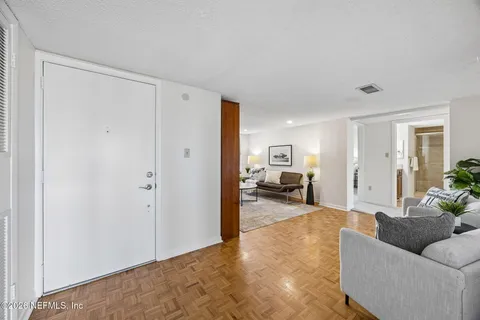 a view of a hallway with wooden floor and a livingroom