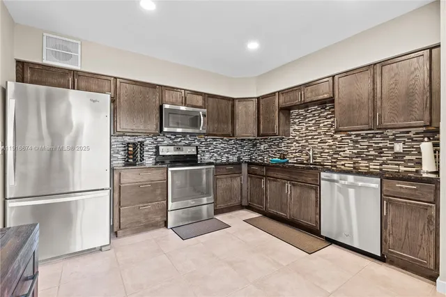 a kitchen with granite countertop a refrigerator sink and microwave