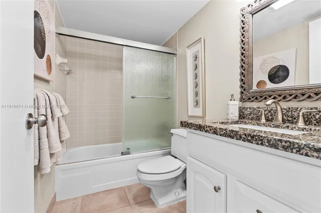 a bathroom with a granite countertop sink mirror vanity and toilet