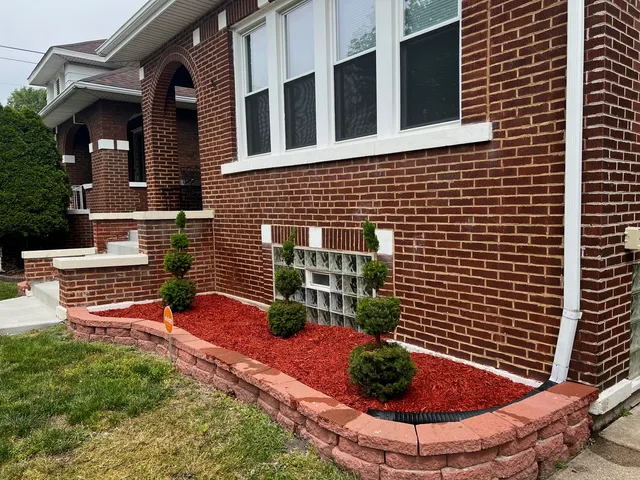 a view of a backyard with plants and brick wall