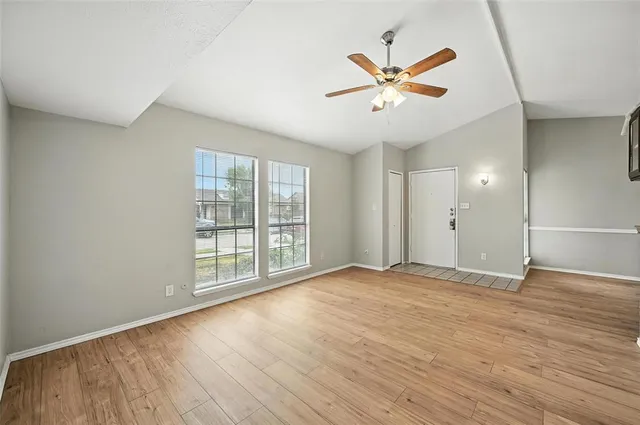 a view of an empty room with window and wooden floor