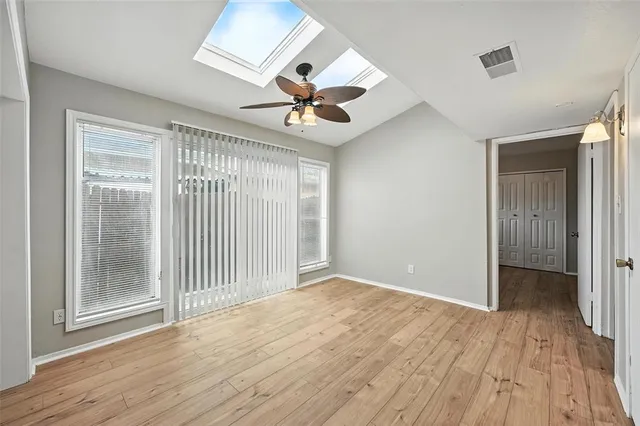 a view of empty room with wooden floor and fan