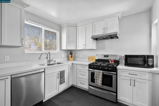 a kitchen with white cabinets stainless steel appliances and sink