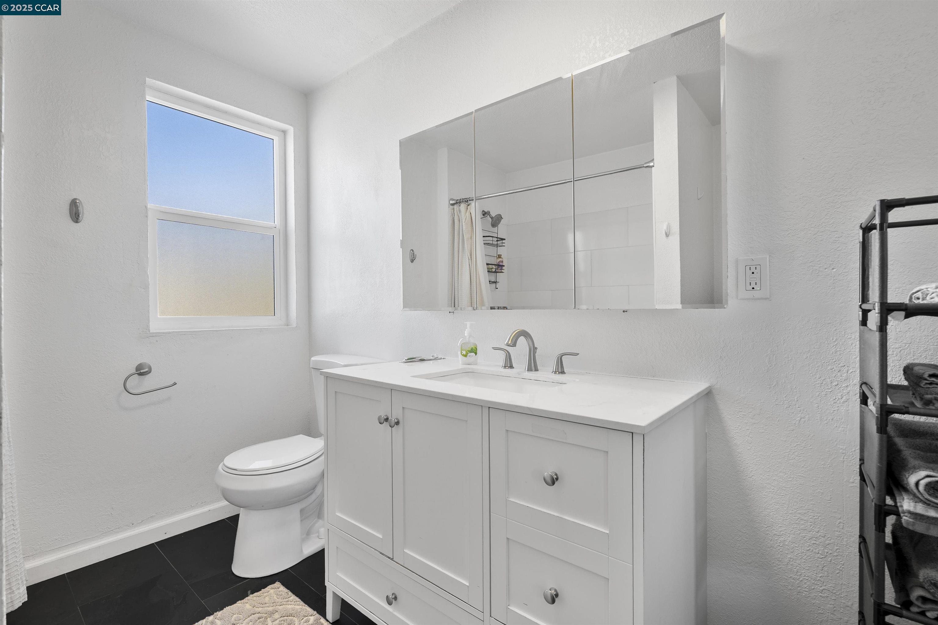 874 36th Street Oakland, CA 94608 - Photo 26 of 41 a bathroom with a toilet a sink a vanity and mirror