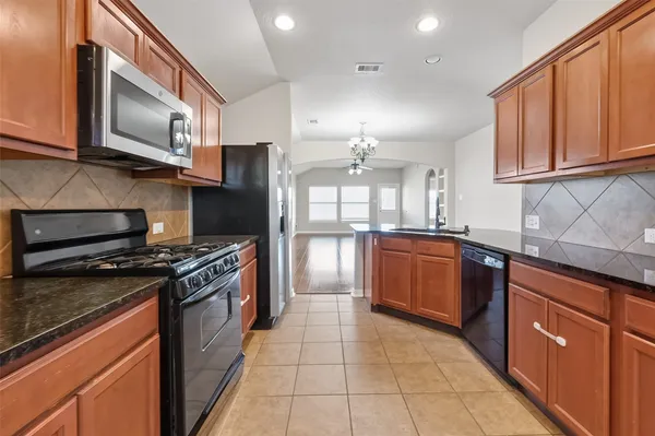 a large kitchen with stainless steel appliances granite countertop a stove top oven a sink dishwasher a refrigerator and cabinets with wooden floor